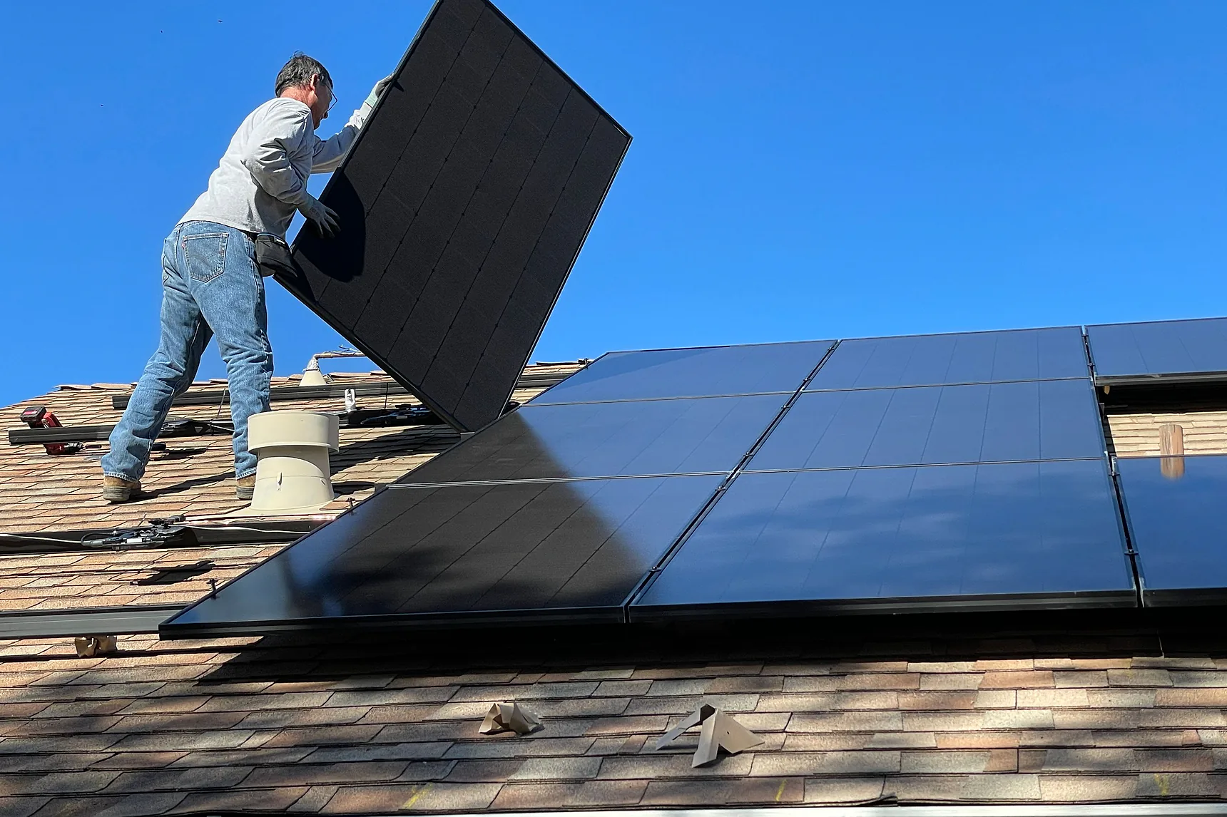Solar installer lifting a panel onto a residential roof