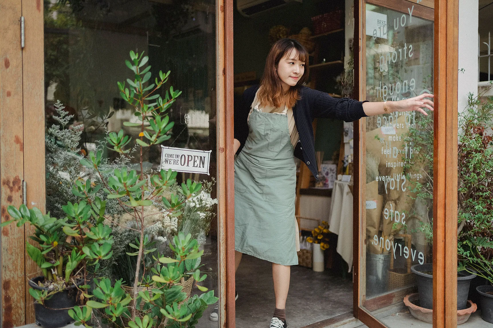 Owner opening the door of a small local shop with an open sign