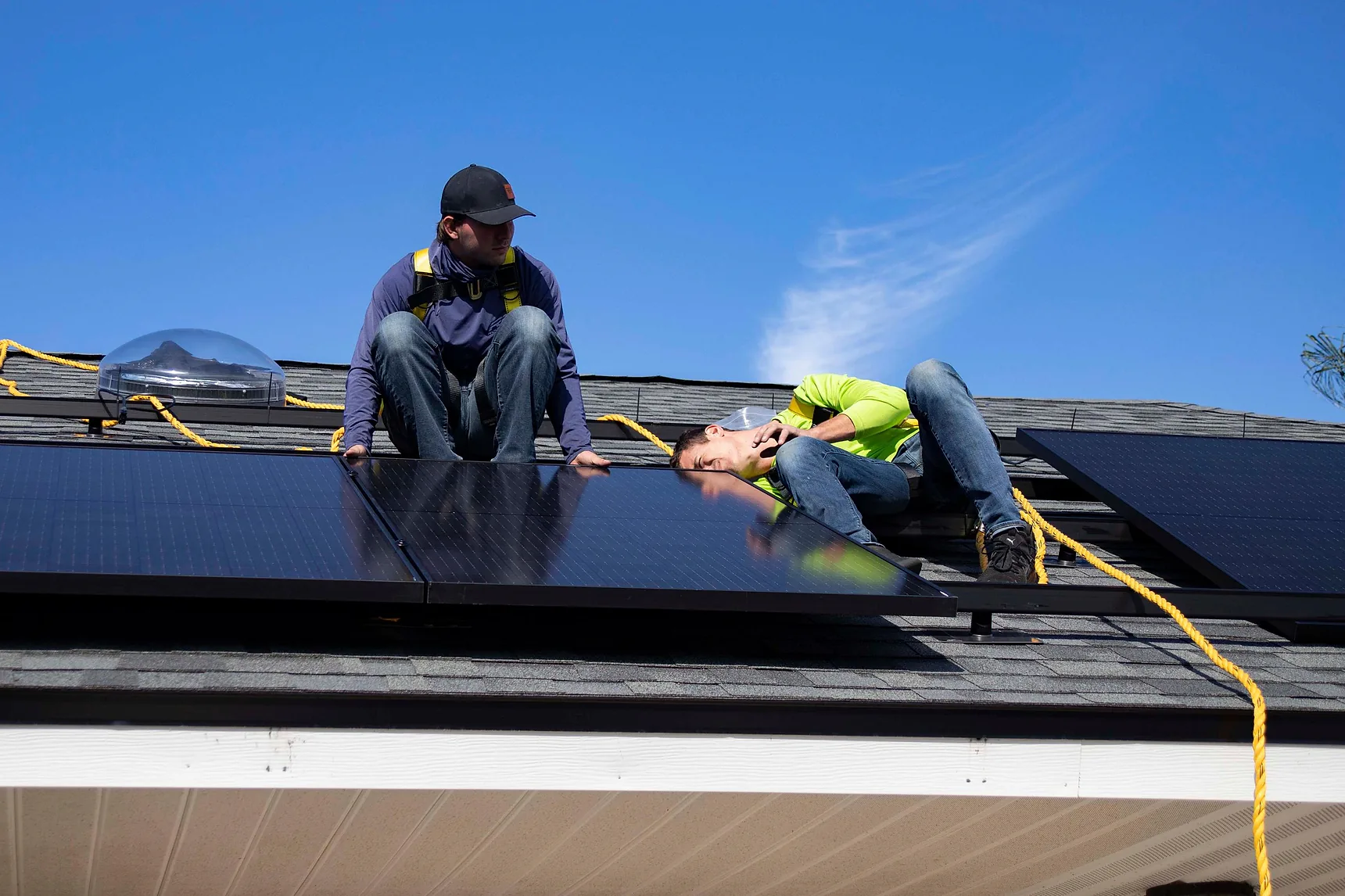 Two solar installers fitting panels on a residential roof