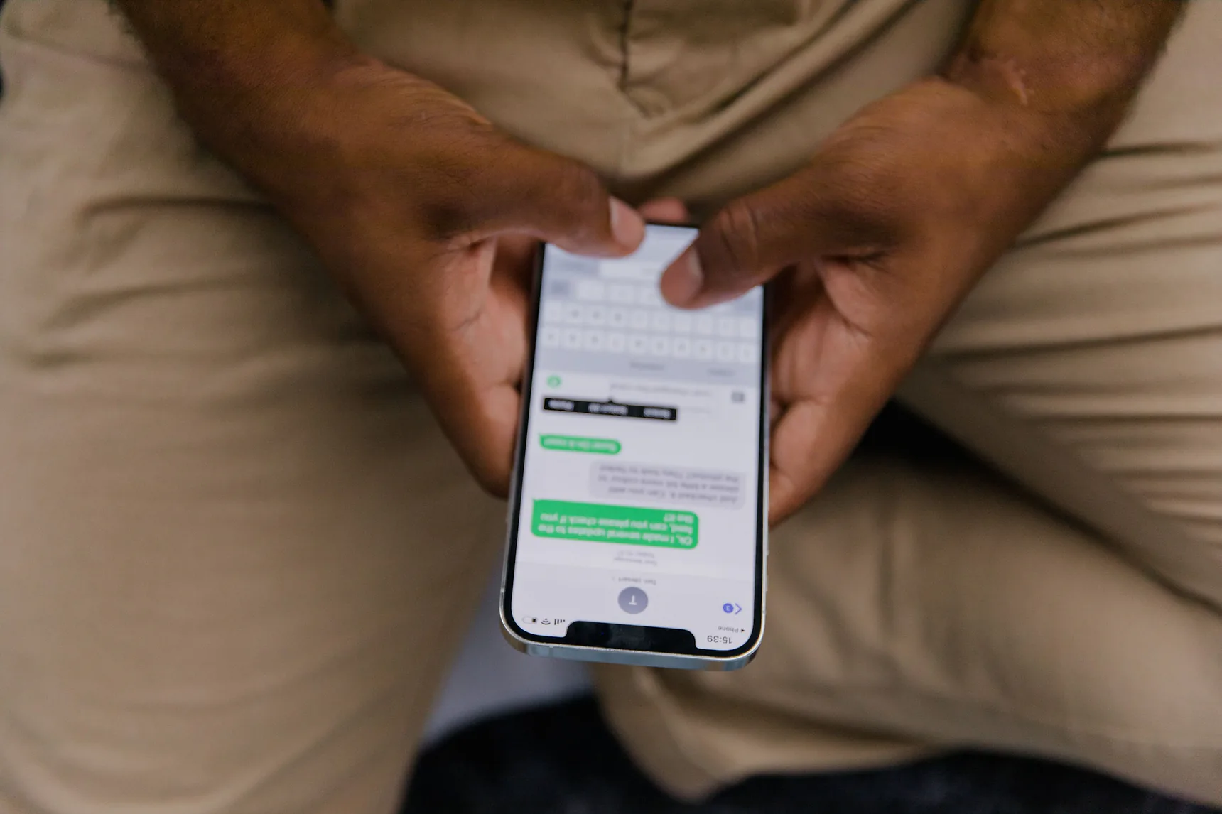Close-up of hands texting on a smartphone showing a message thread