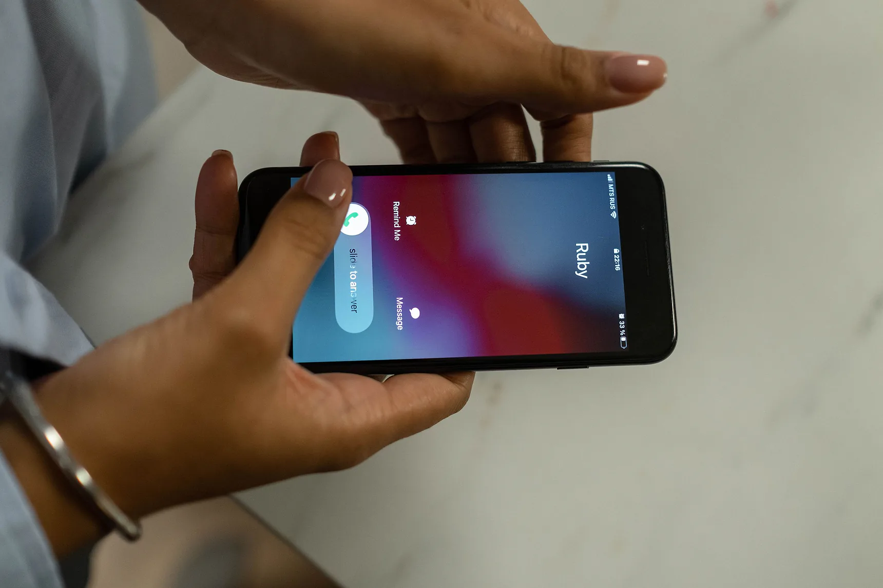 Hands holding a smartphone with an incoming call on screen