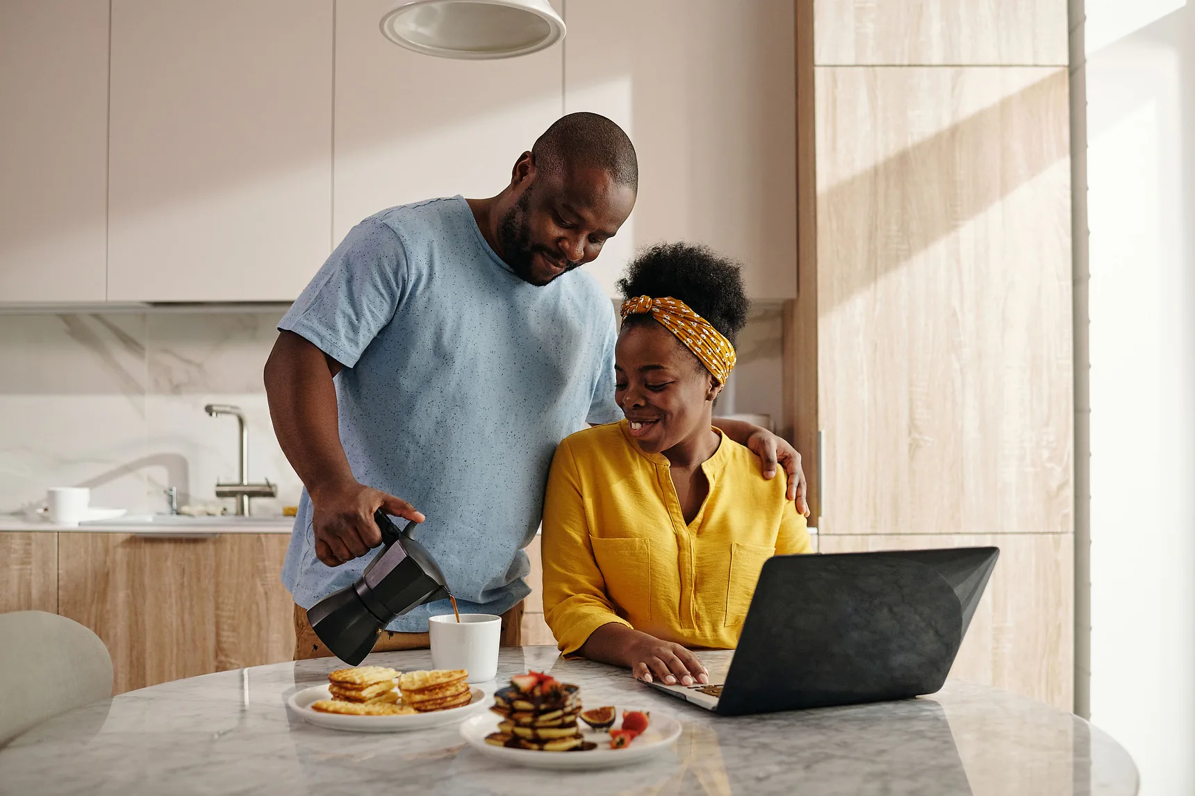 Couple at a kitchen table using a laptop