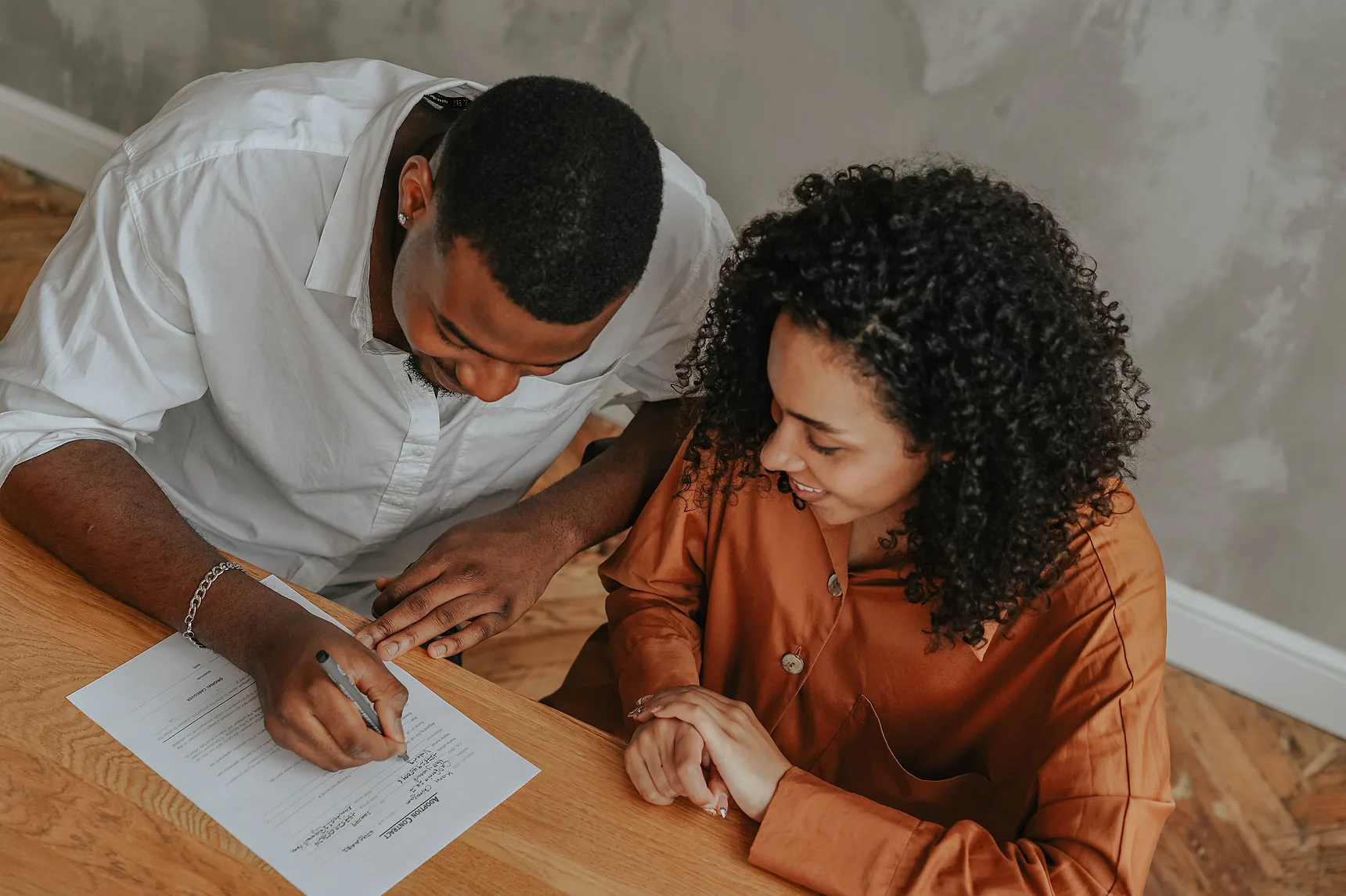 Couple at home signing an agreement at a wooden table