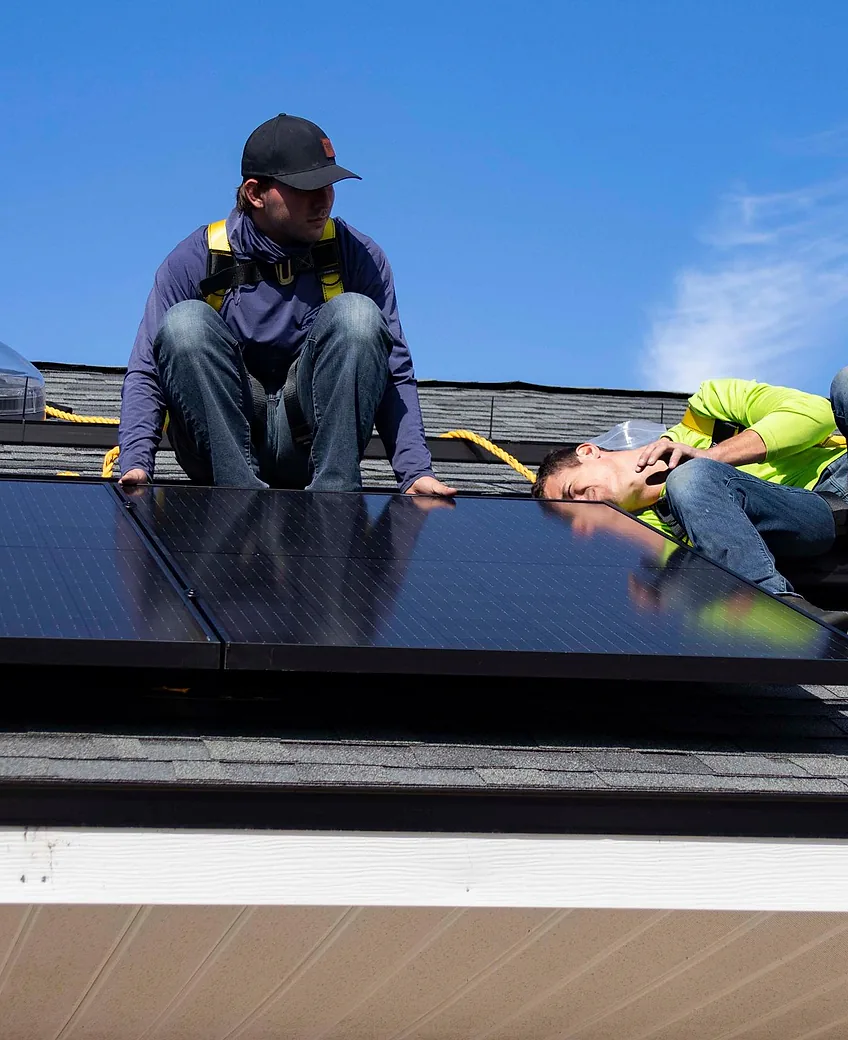 Two solar installers working on a residential roof
